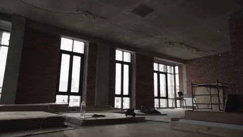 Dark large hall with big black framed windows, planks on floor and scaffolding Stock Footage 99612802