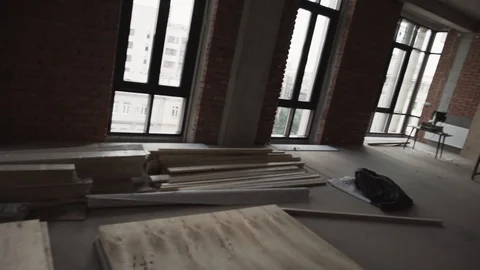 Dark large room with big black framed windows, planks on floor and scaffolding Stock Footage 99612833