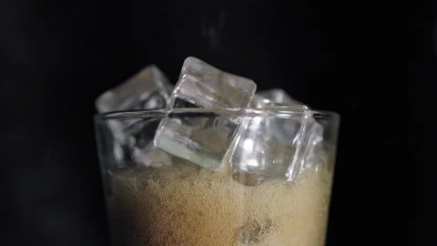 Dark Liquid Poured Over Ice Cubes in Glass Night Scene Stock Footage 340124238