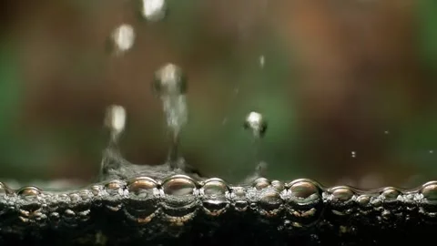 Dark liquid surface with many small bubbles forming and rising Stock Footage 322874090