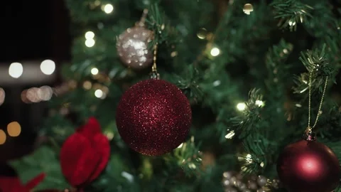 A dark lit decorated Christmas tree at nighttime with bright red sparkly ornamen Video stock 328595929