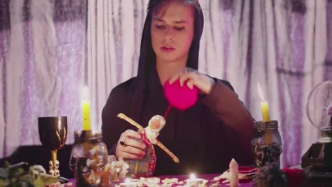 Dark magic voodoo witch performing ritual and casting spell piercing doll with Stock Footage 143511997