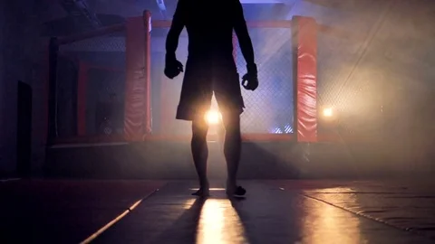 A dark male shape walks away from a fighting cage. Stock-Footage 80928186