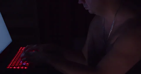 In the dark, a man with no clothes to his waist and a silver chain is working Stock Footage 316856346