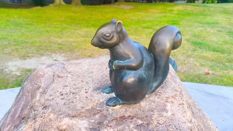 Dark marble squirrel statue perched on a rock at an outdoor park. Summer day Video stock 317134259