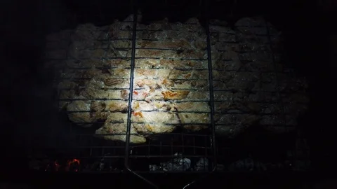In the dark, meat is grilled on the grill in the rays of a flashlight. 動画素材 115898025