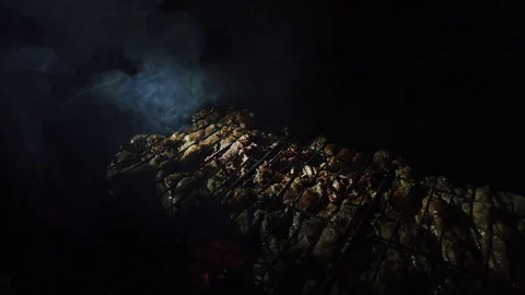 In the dark, meat is grilled on the grill in the rays of a flashlight. 動画素材 115898317