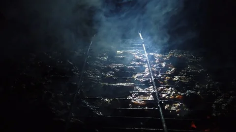 In the dark, meat is grilled on the grill in the rays of a flashlight. 動画素材 115898625