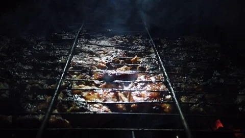 In the dark, meat is grilled on the grill in the rays of a flashlight. Vídeos de archivo 115898714