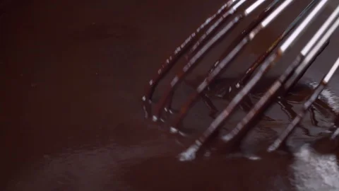 Dark melted chocolate flows from a whisk Stock Footage 123303055