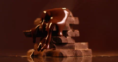 Dark melted chocolate pouring over stack of broken pieces chocolate in slow Stock Footage 163045771