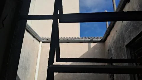 Dark metal window bars framing a clear blue sky background Stock Photos