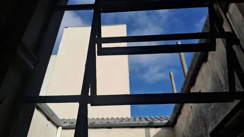 Dark metal window frame looking out at clear blue sky Stock Photos