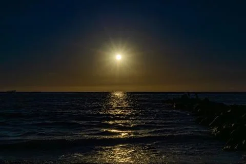 Dark mode of the Sun shining over the ocean Stock Photos