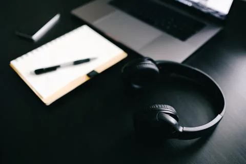 Dark modern workplace with a notebook for recording, a laptop, headphones Stock Photos