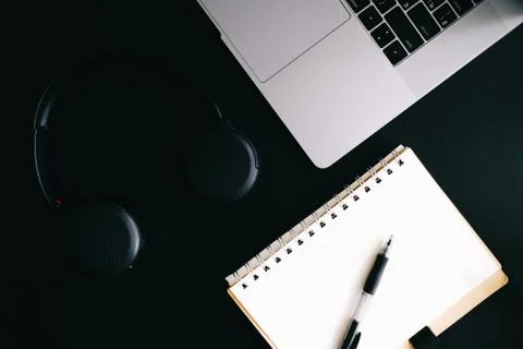 Dark modern workplace with a notebook for recording, a laptop, headphones Stock Photos