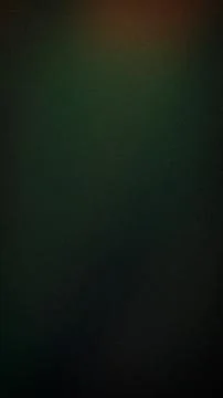 Dark moody grainy gradient background with deep green tones and orange ligh.. Stock Photos