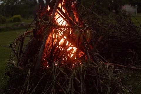 A dark, moody image of a bonfire made of thick branches and adorned. 스톡 사진