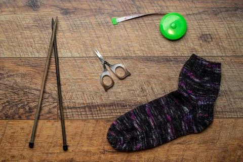 Dark multi colored knitted sock on a wooden background Stock Photos