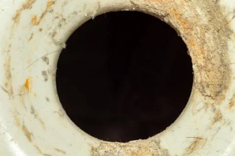 A dark mysterious hole in aged ceramic surface texture with rough edges Stock Photos