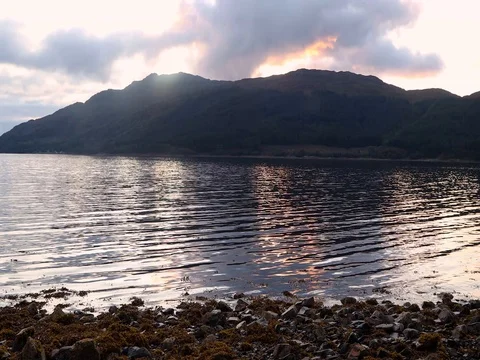 Dark Mysterious Mountains throw long shadows across the rippling waters of a Stock-Footage 80146262