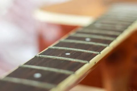 Dark neck guitar without strings with frets of light wood on a brown plaid Foto stock