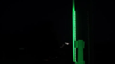 A dark night sky with a green lighted pole Stock Footage 296093711