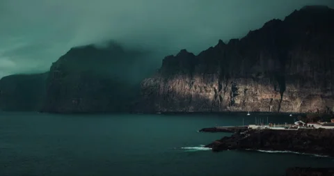 Dark ocean landscape with gray storm clouds over black volcanic cliffs. Fog Stock Footage 240497038