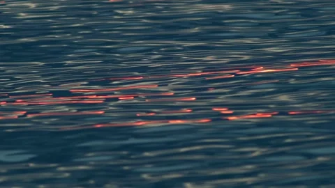 Dark Ocean Surface With Crimson Sunset Reflections and Rolling Wave Patterns Видео 334829679