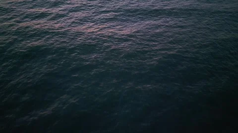 Dark ocean surface at night with gentle waves and a subtle glow from the sky. A Stock Footage 301700092