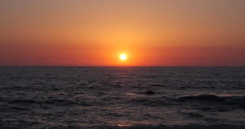 Dark ocean waves at sunset with sun above horizon Video stock 135044904
