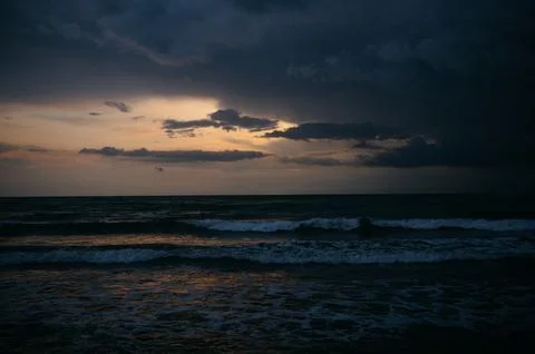 Dark ocean waves under cloudy sky at sunset with dramatic lighting Stock Photos