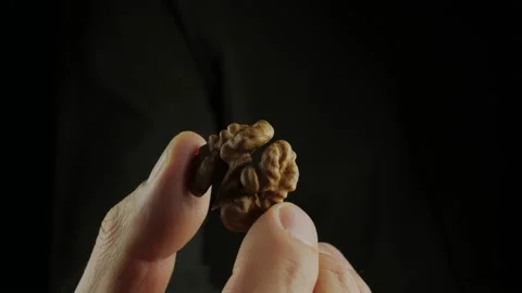 On the dark one, the walnut kernel is in close-up, rotating on the fingers of Stock Footage 166580928