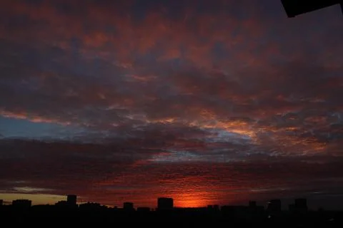 A dark orange sunset that illuminates the clouds flying by over the already nigh Foto stock