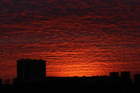 A dark orange sunset that illuminates the clouds flying by over the already nigh Foto stock