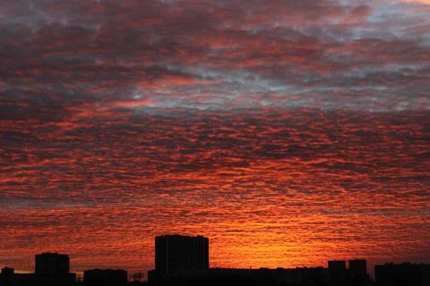 A dark orange sunset that illuminates the clouds flying by over the already nigh Foto stock