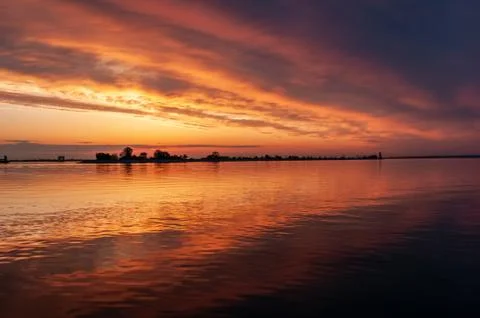 Dark orange sunset spring evening on the river or reservoir Stock Photos
