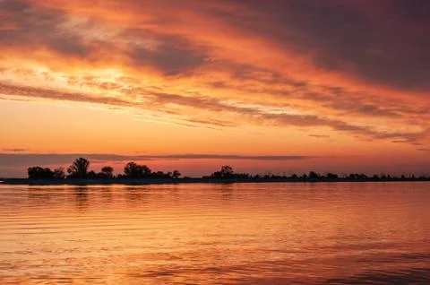 Dark orange sunset spring evening on the river or reservoir Stock Photos