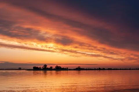 Dark orange sunset spring evening on the river or reservoir Stock Photos