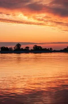 Dark orange sunset spring evening on the river or reservoir Stock Photos