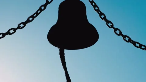 Dark outline of a large metal bell on blue sky background. Видео 219728906