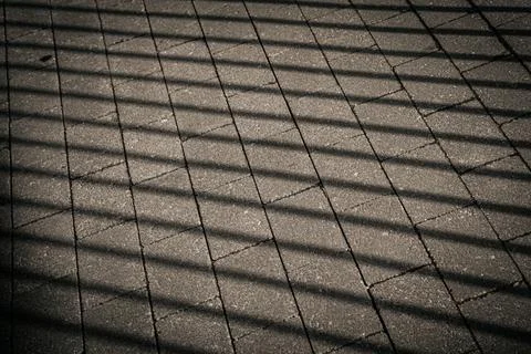 Dark, parallel shadows from a fence create a geometric pattern. Stock Photos