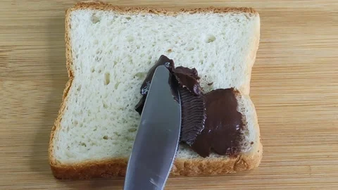 Dark paste is spread on white toast bread Stock Footage 199019493
