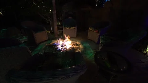 Dark patio lounge circle with wicker chairs around a fire pit Stock Footage 345540650