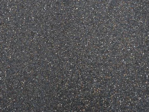 Dark pavement with a grainy pockmarked texture. Full screen photo. Background Stock Photos