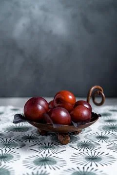 Dark photography of plums on a retro pattern tablecloth. Moody picture of sea Stock Photos
