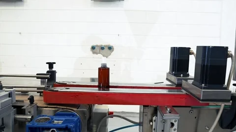 A dark plastic bottle containing liquid moves along an automated conveyor belt Stock Footage 311998538