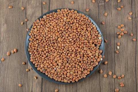 A dark plate full of dried raw brown kidney beans Stock Photos