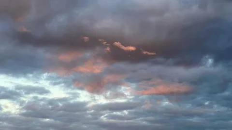Dark pre-storm sky with multi-colored flashes of sunlight at sunset Stock Photos