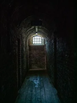 Dark prison corridor with barred window Фото